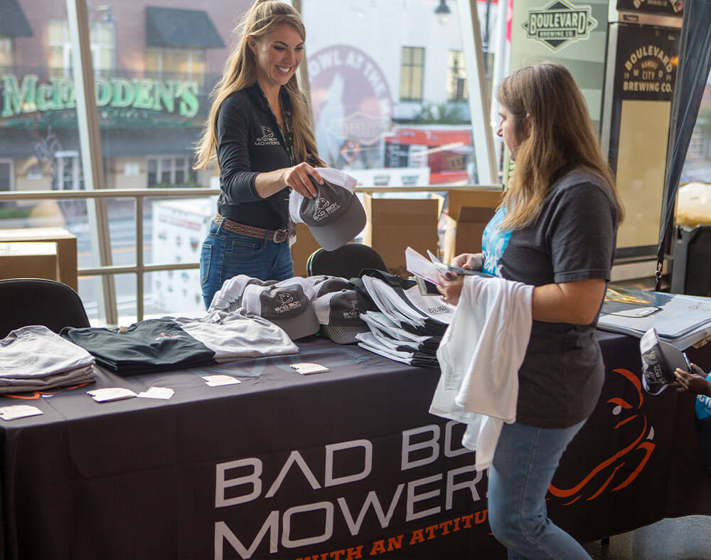 Mallory, Bad Boy Mowers Spokesperson handing out merch to fans at Outlaw Days.